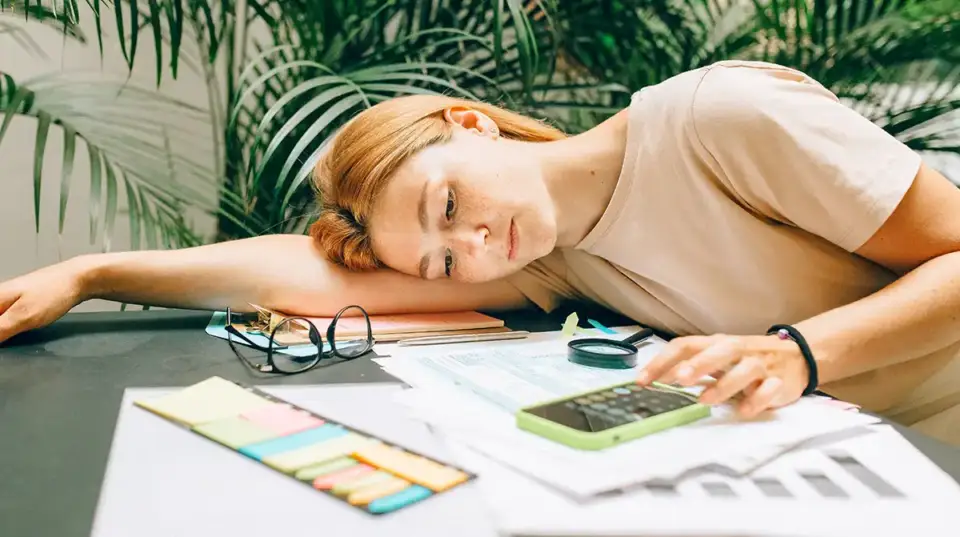 A woman is overwhelmed by tax preparation, and lies her head down on table.