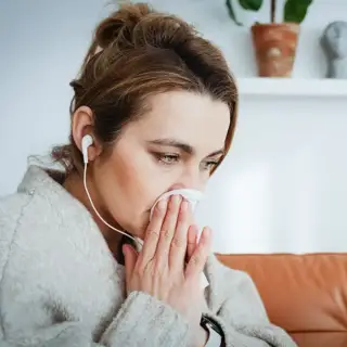 A woman blows her nose as she suffers from spring allergies
