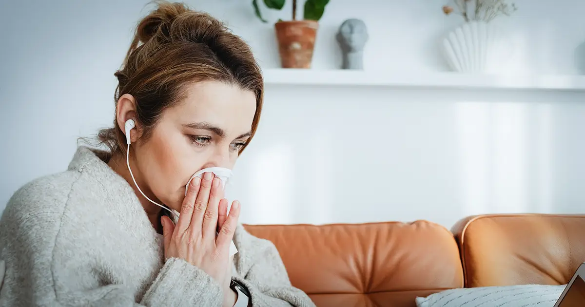 A woman blows her nose as she suffers from spring allergies