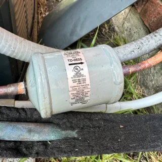 HVAC technician's hands holding a vacuum pump on copper refrigerant lines during air conditioning system evacuation in Rowlett