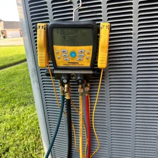 Fieldpiece manifold gauge set connected to outdoor AC unit showing vacuum pressure readings during evaporator coil replacement in Rowlett