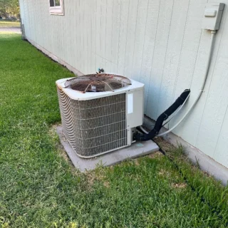 New R454B heat pump unit installed on concrete pad against white residential siding in Mesquite, TX