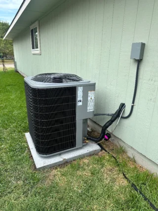 New R454B heat pump system installed outside light green house with conduit running to outdoor unit mounted on concrete pad