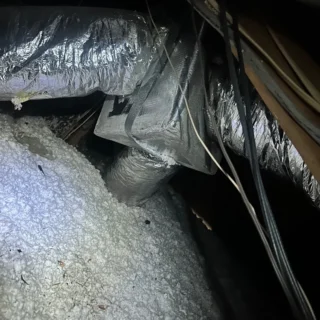 Technician inspecting HVAC ductwork and insulation during diagnostic service in Mesquite home