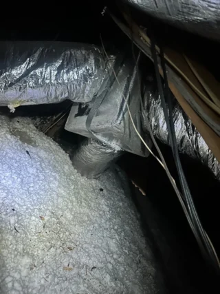 Technician inspecting HVAC ductwork and insulation during diagnostic service in Mesquite home
