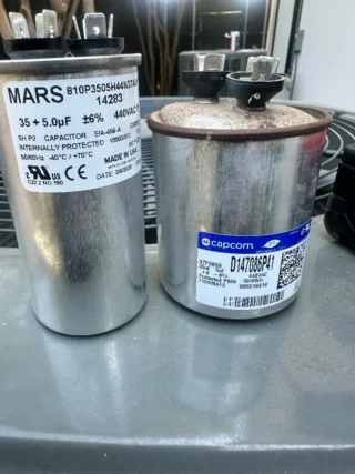 Two failed dual run capacitors removed from air conditioning systems in Mesquite, TX showing wear and oxidation damage.