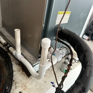 AC drain pan with float switch and white PVC condensate lines, inspected during Garland service call