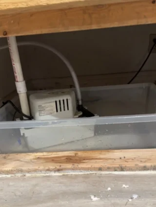 White condensation pump with gray drain hose rerouted inside HVAC unit for improved drainage in Sunnyvale home