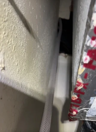New condensation drain hose routed along exterior wall to prevent buildup and clogging issues