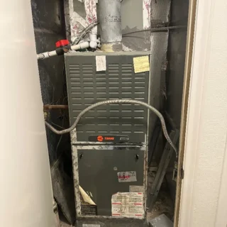 New Trane HVAC furnace unit installed in closet with metal ductwork and flexible connectors visible above