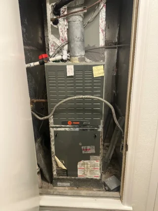 New Trane HVAC furnace unit installed in closet with metal ductwork and flexible connectors visible above