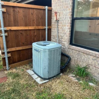 New air conditioning unit installed on concrete pad beside brick home in Mesquite, TX